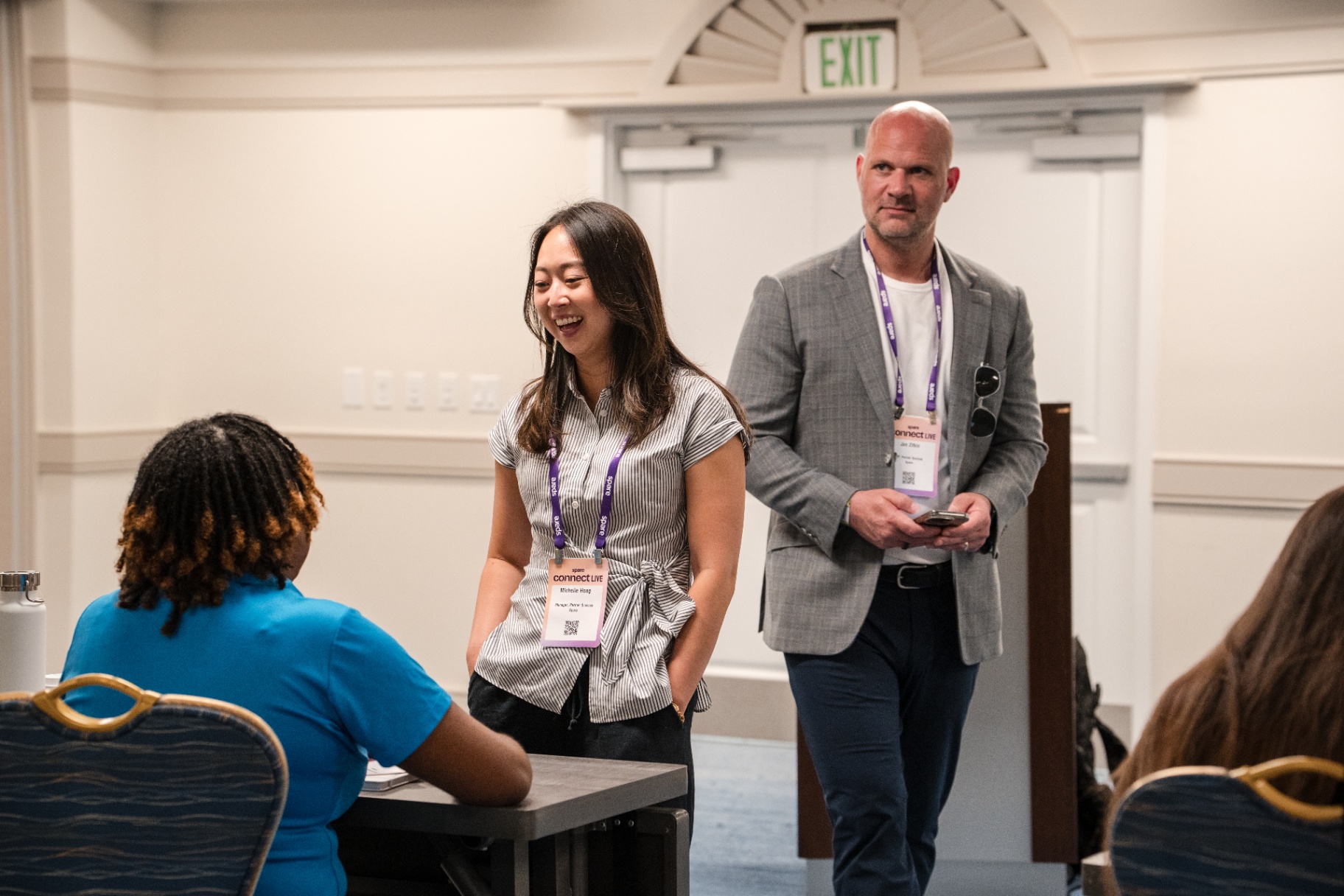 Michelle Hong and Jan Zilen smiling with an attendee between sessions on Day 2