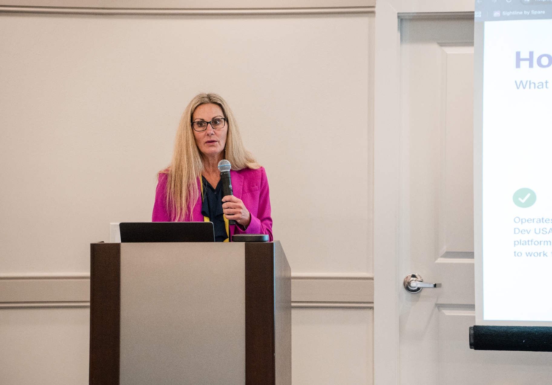 Close-up of the speaker in pink blazer at the podium during the VoTran session