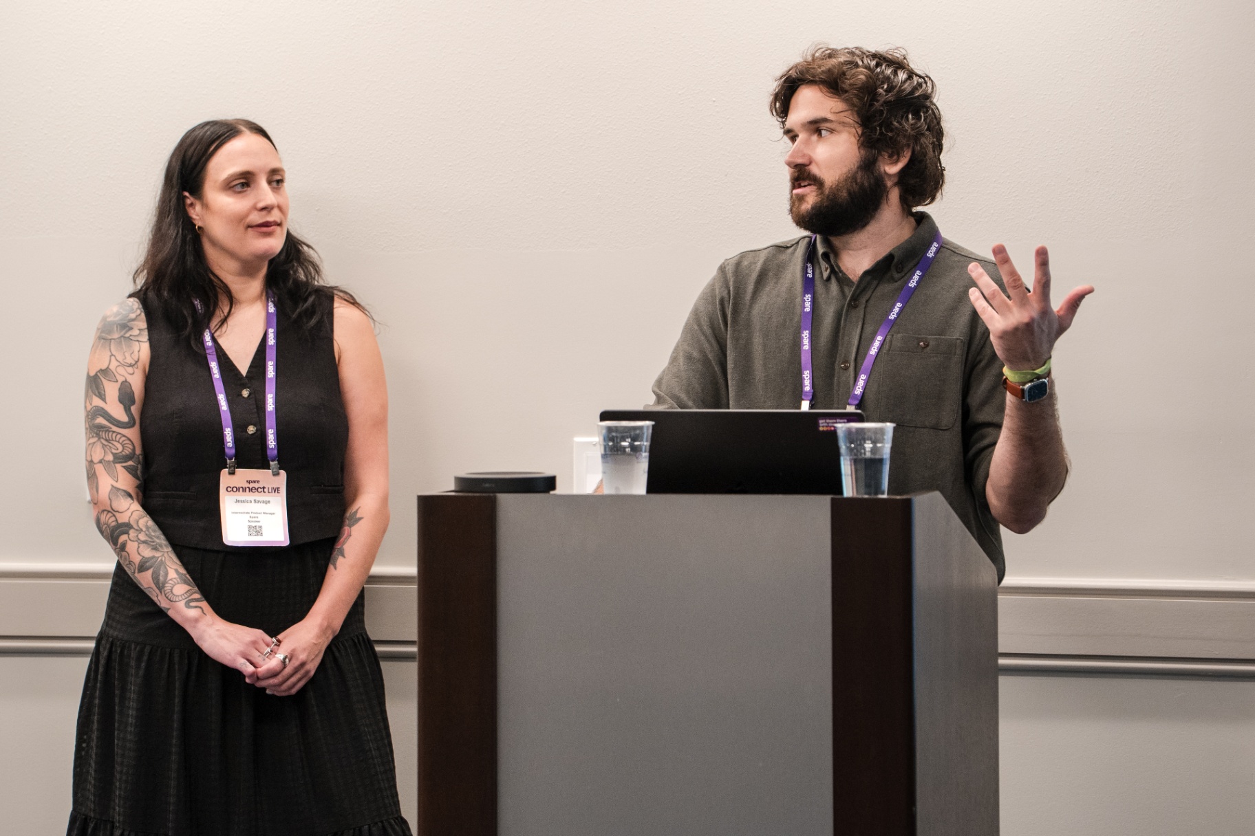 Co-presenter gesturing while speaking at the podium during Day 1