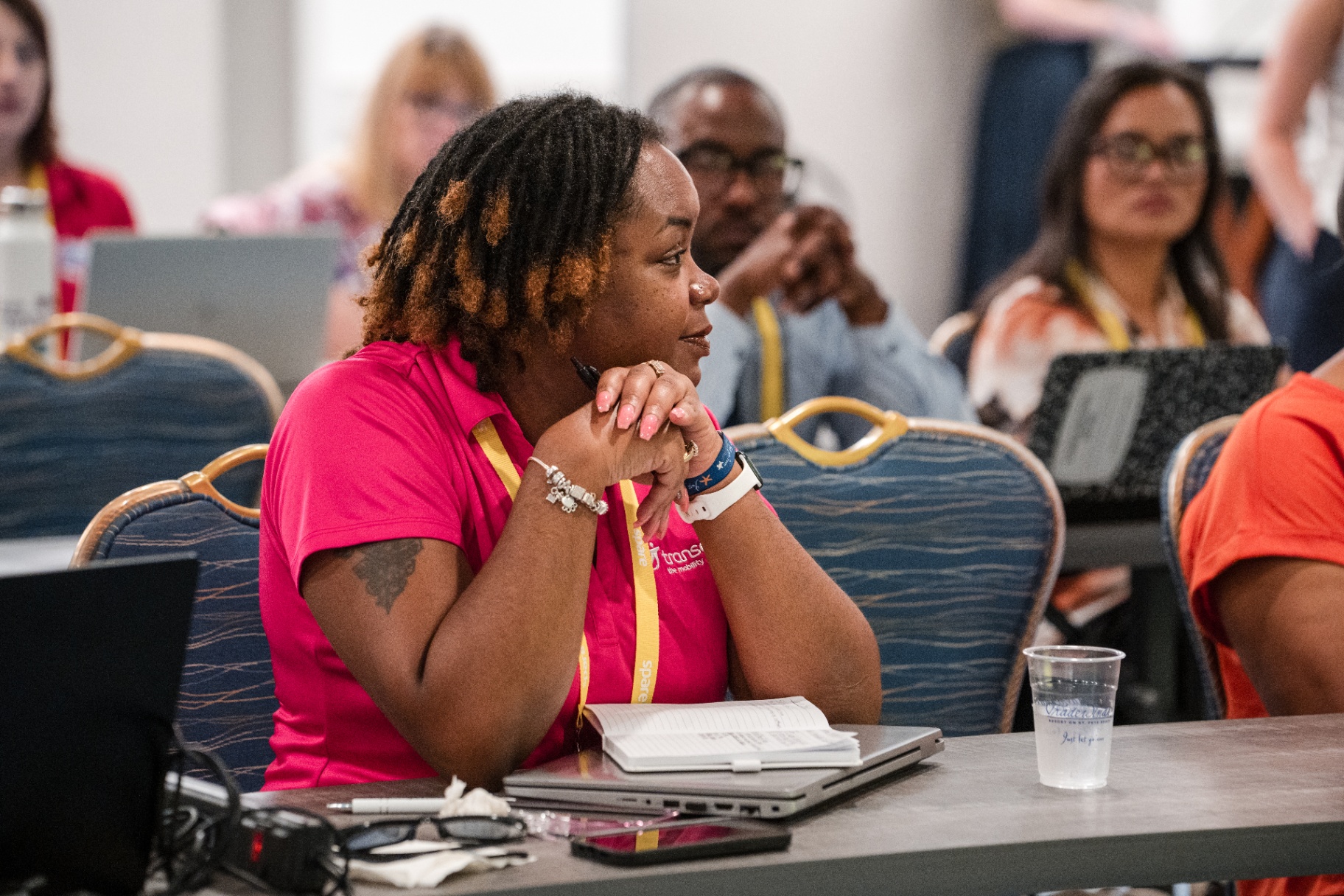 Attendee in a bright pink shirt listening during a Day 1 session