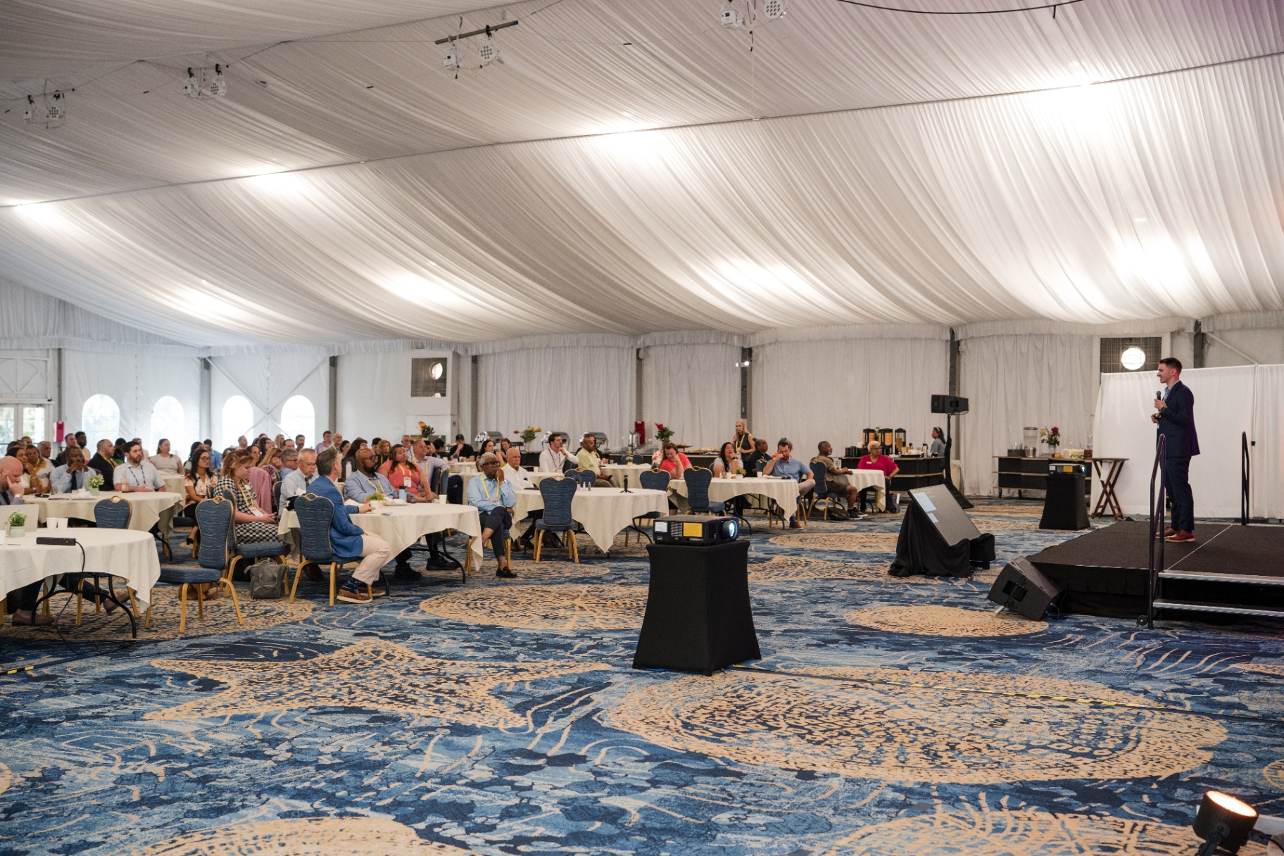 Wide view of the Day 1 audience inside the tented ballroom