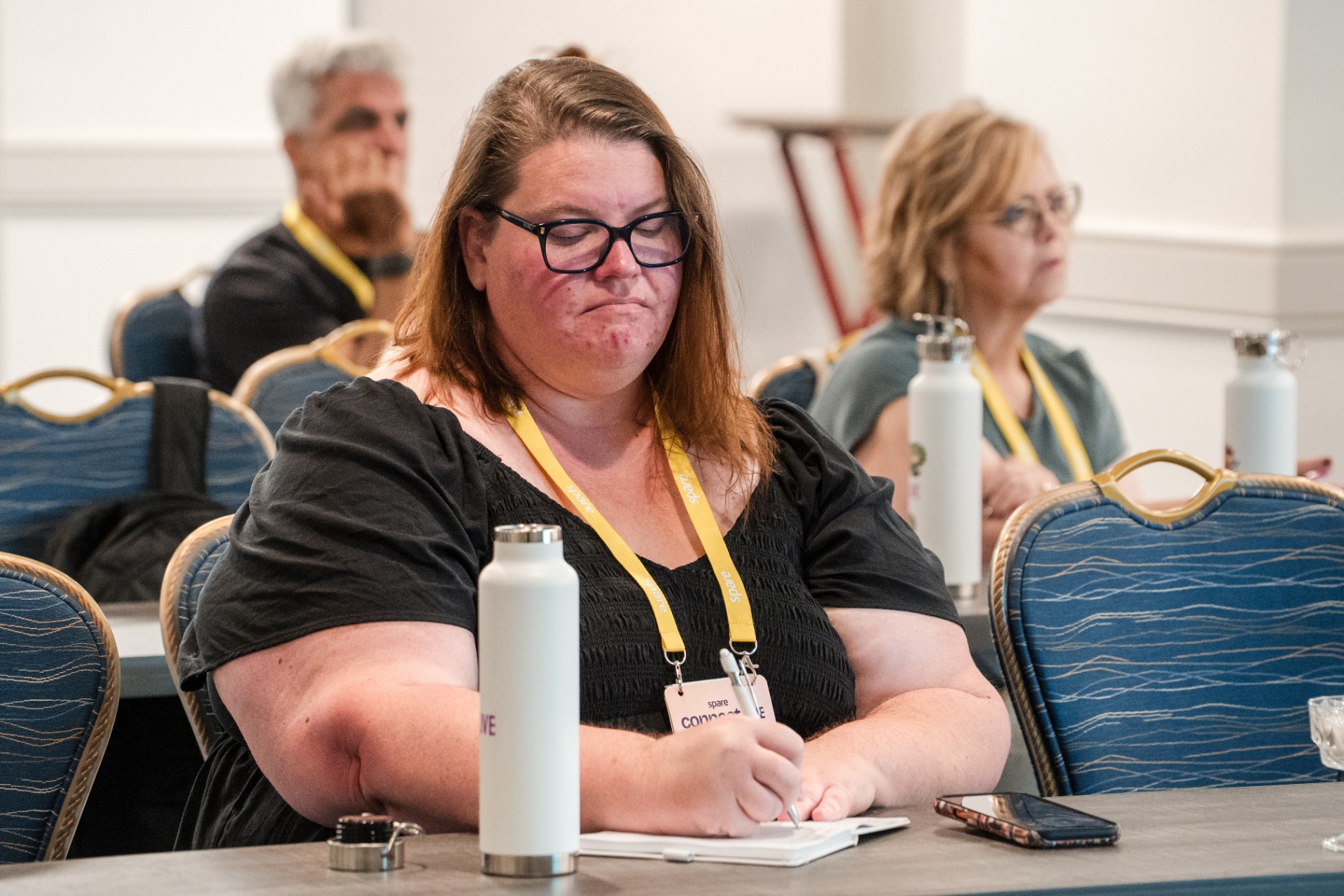 Attendee writing notes while listening during a breakout session