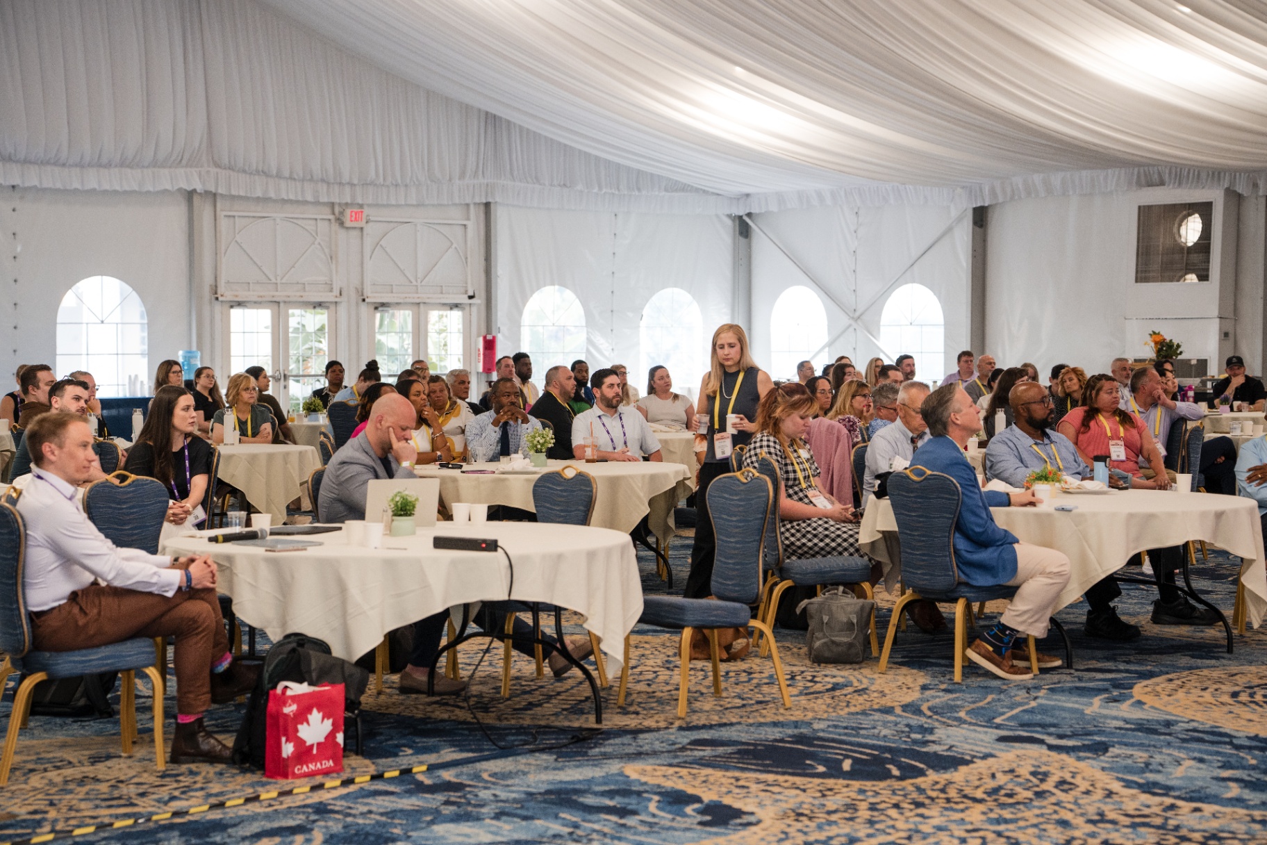 Engaged audience seated at round tables during Day 1