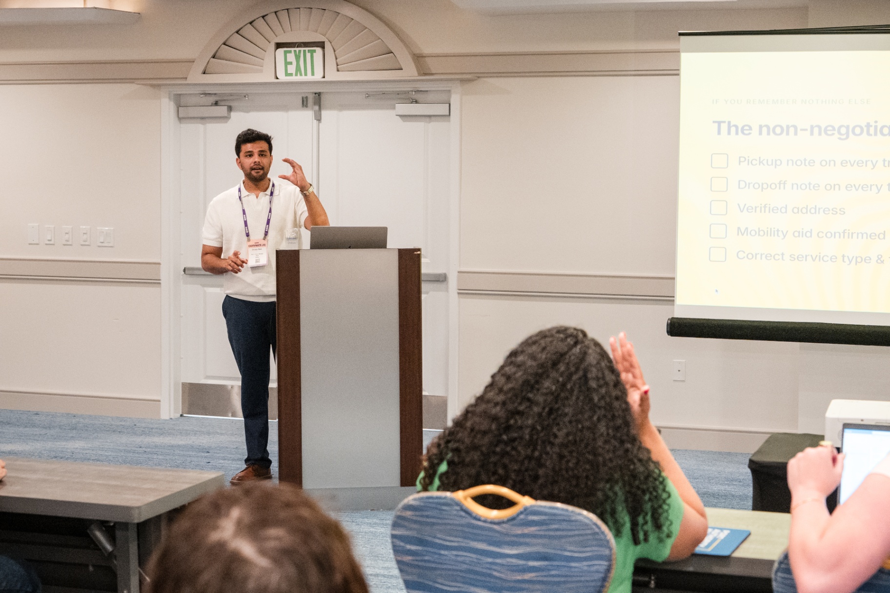 Speaker gesturing at the podium during a Day 1 breakout