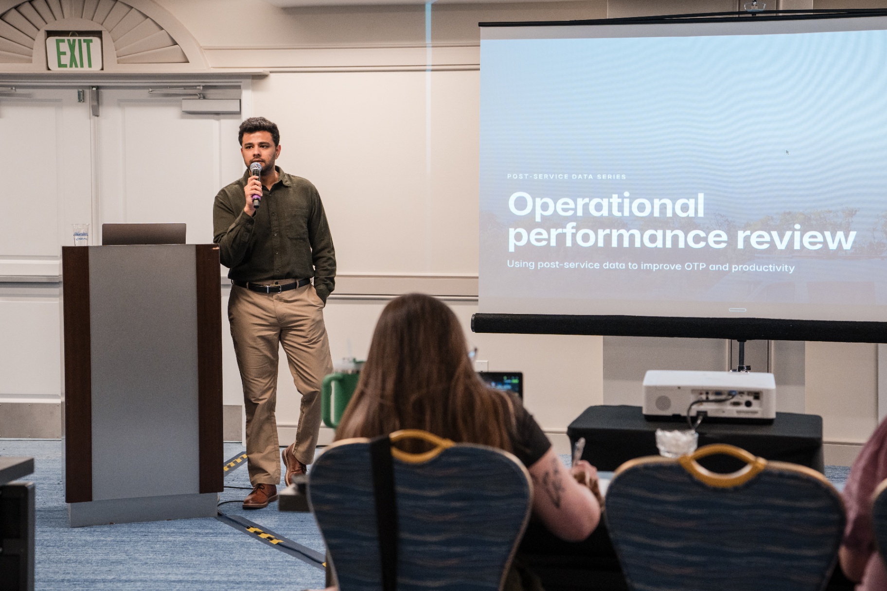 Presenter at the podium beside the 'Operational performance review' title slide