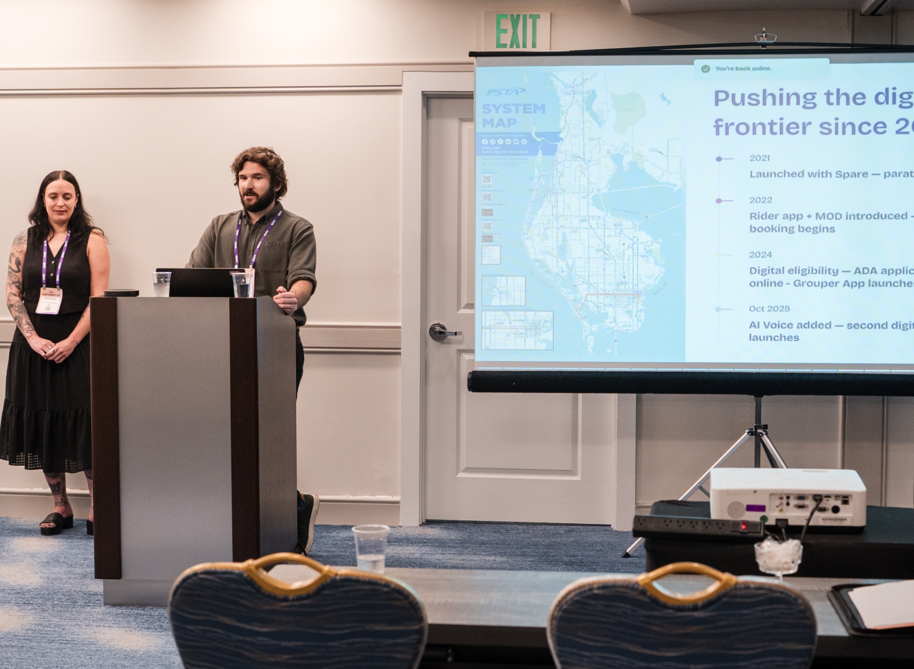 Co-presenters at the podium with PSTA system map slide behind them