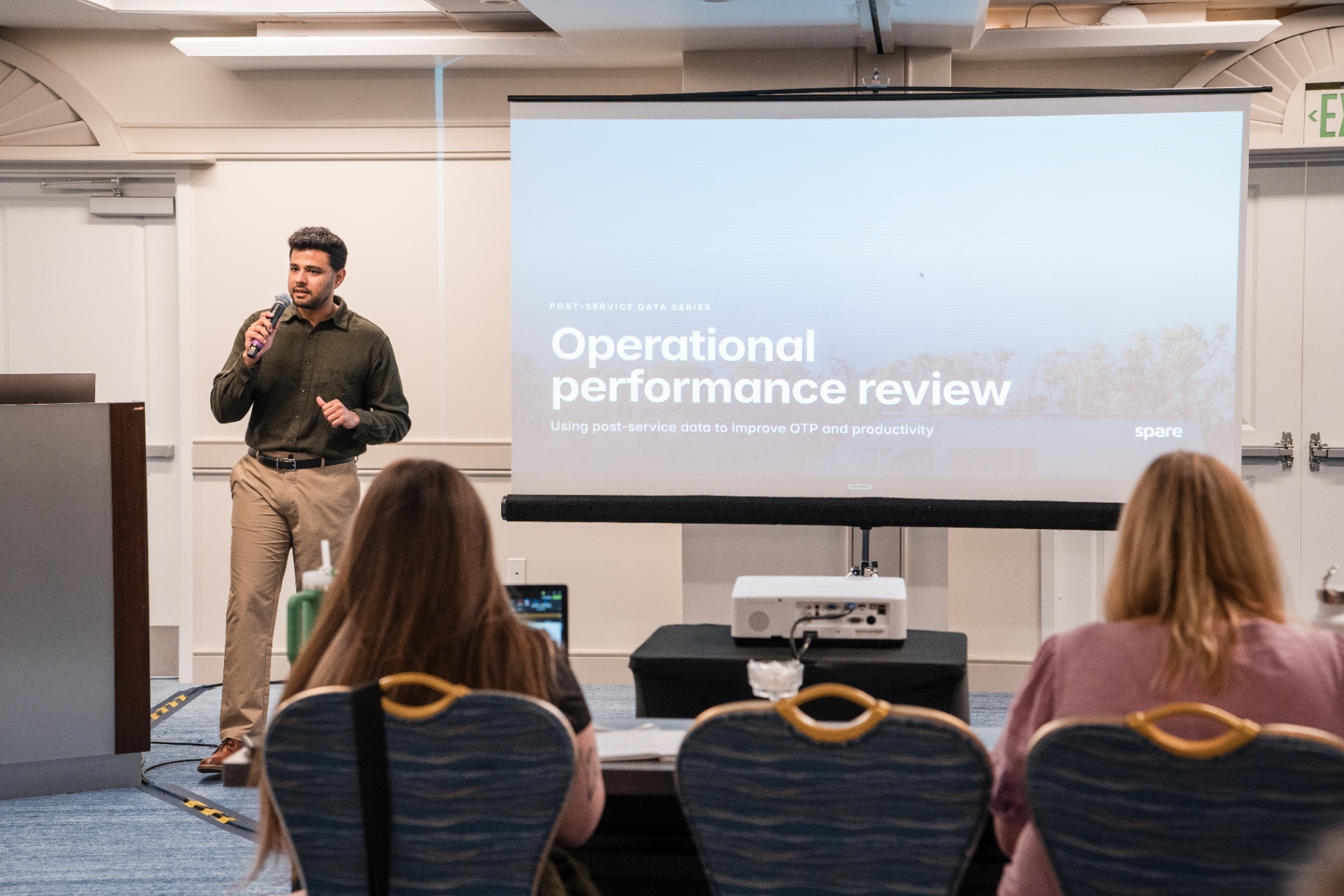 Wide view of the 'Operational performance review' title slide with presenter at the podium